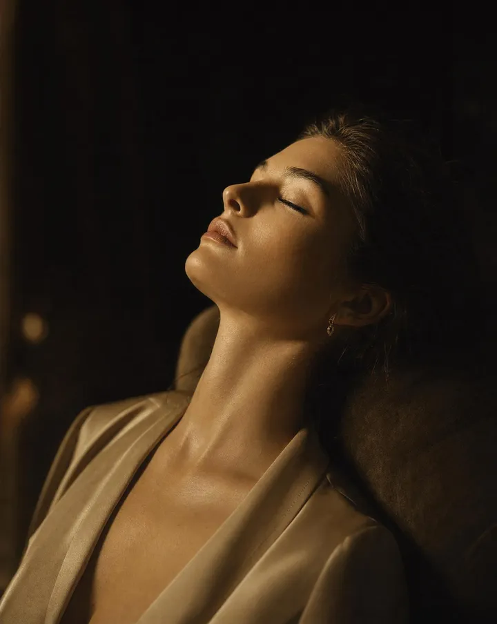 A person resting with eyes closed in warm, soft light, calm and considered